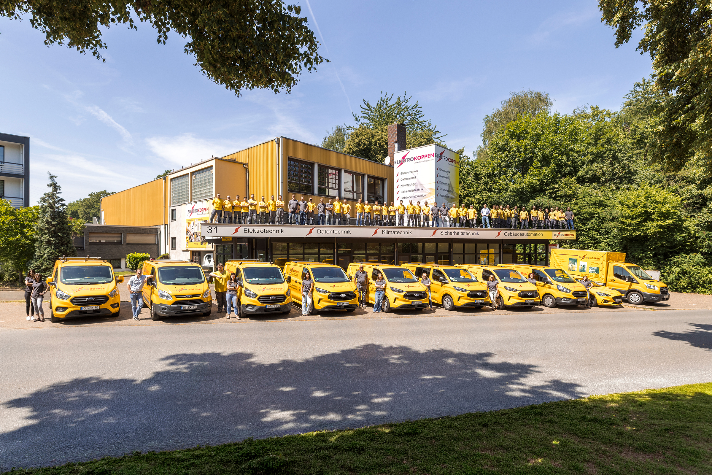 Gruppenfoto von allen Mitarbeitenden auf dem Dach des Elektro Koppen Gebäudes.